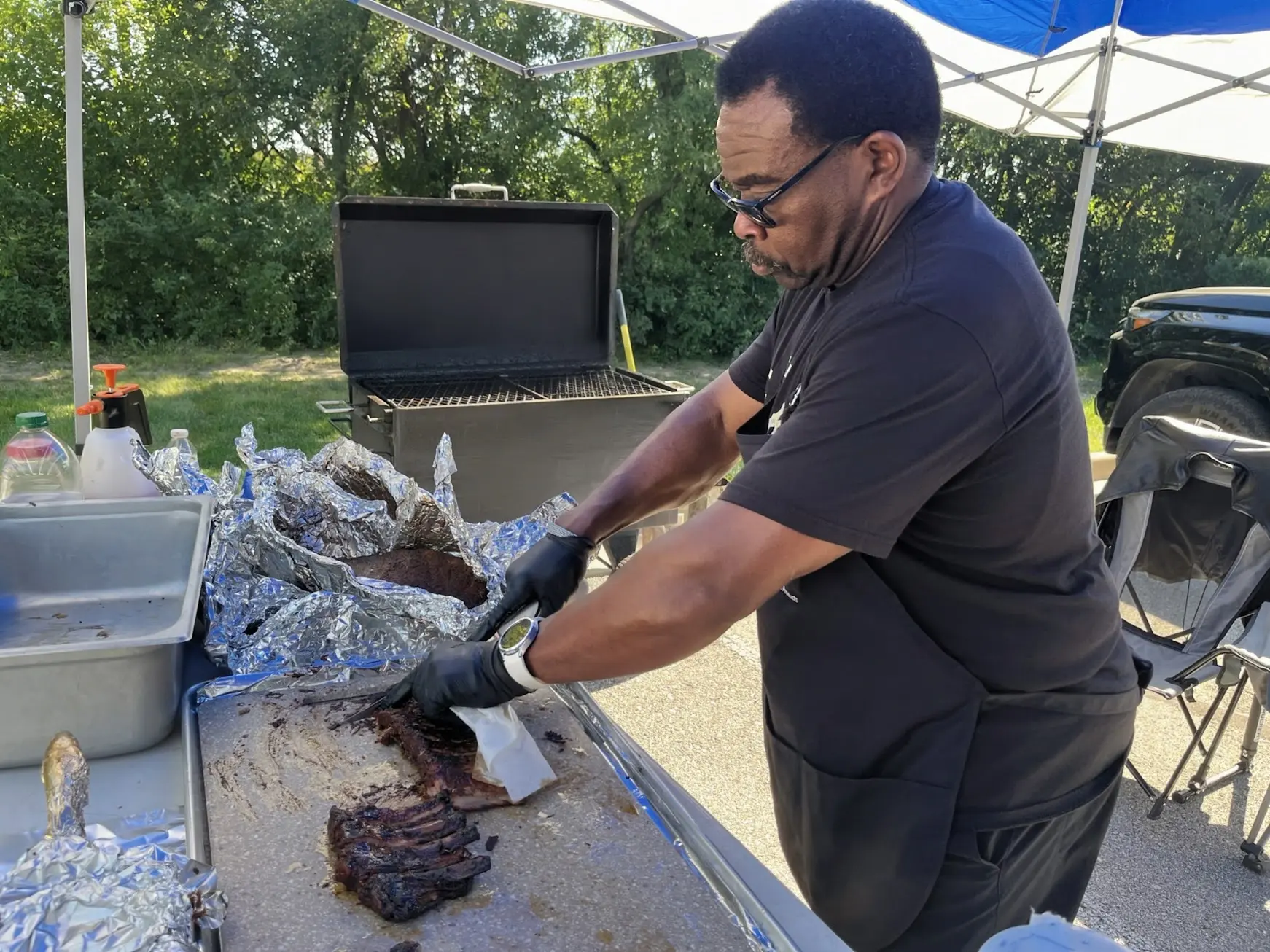 Team member slicing smoked ribs at the competition table